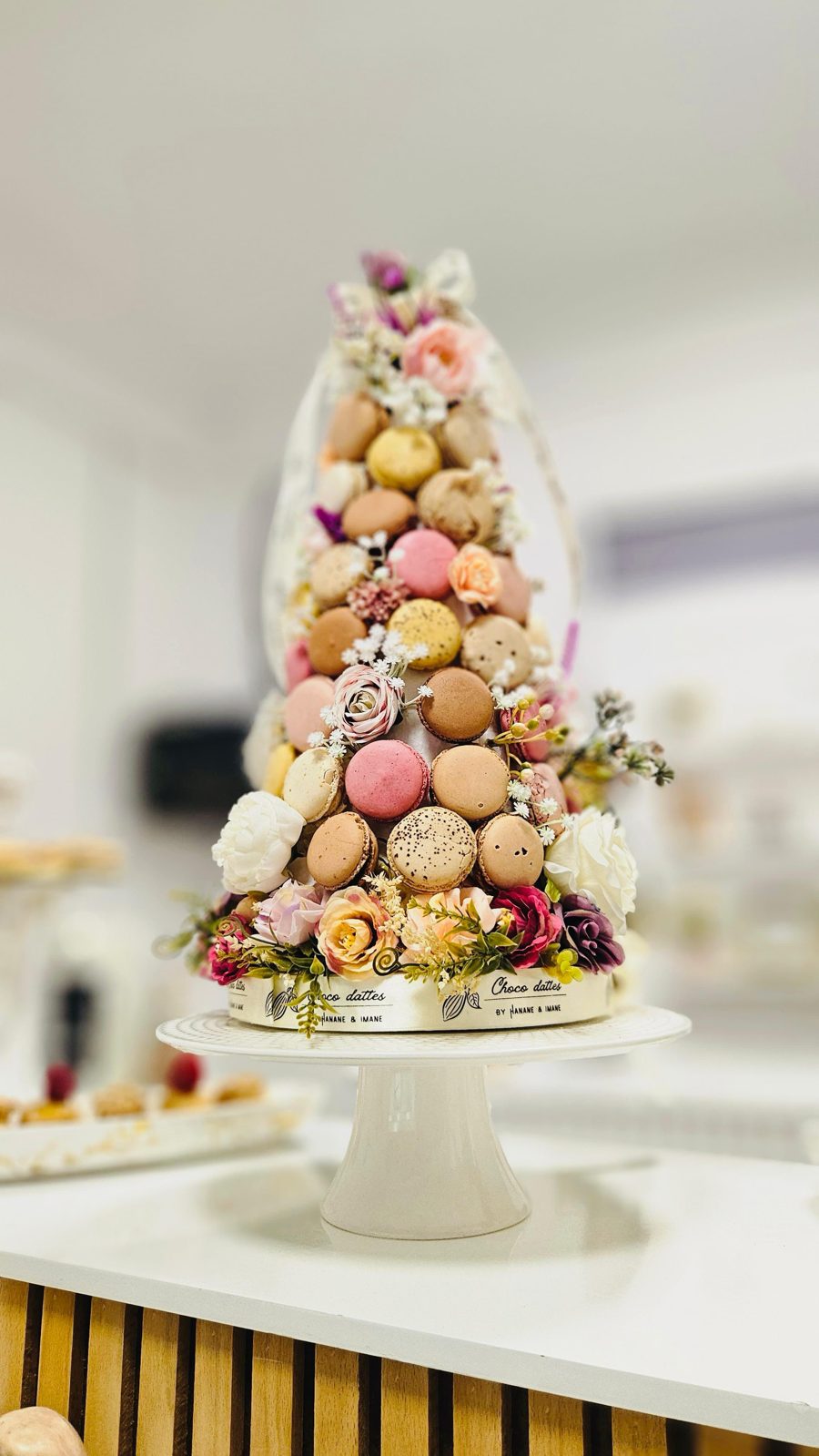 Tour de macarons et fleurs sur présentoir blanc